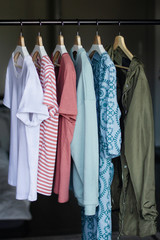 various women's clothing hung in colors on wooden hangers