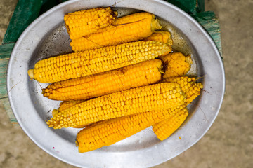 Boiled corn on an aluminum tray. Yellow boiled young corn, useful and tasty food