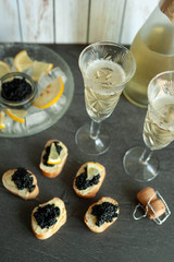 Sturgeon black caviar, sandwiches and champagne on black background