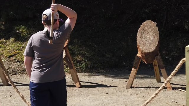 Teenager throws an ax and hits the target in slow motion/high speed.