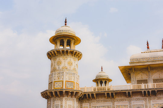 The corner of an ornate yellow stone bulding with a turret.