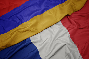 waving colorful flag of france and national flag of armenia.