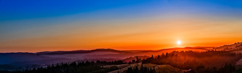 Panorama of sunset over hills, forest, countryside