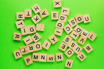 Pile of wooden letters on the surface of a green background, selective focus