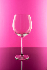 Single Empty Wine Glass on pink background with glare and reflection. Wine concept. 