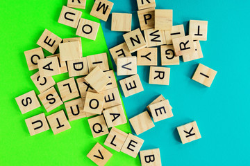 Pile of wooden letters on the surface of a green and blue background, selective focus