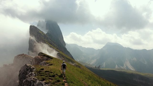 Traveler walking on the ridge of misty Seceda