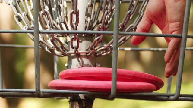 Man retrieves disc golf putter from basket, slow motion, closeup