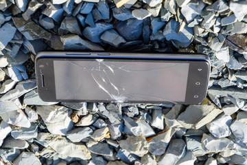 Frustrated phone on the rocks. Glass shattered on rocks on a sma