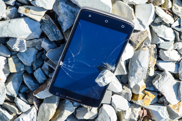 Frustrated phone on the rocks. Glass shattered on rocks on a sma
