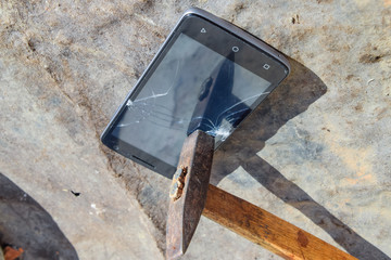 Hammer and smartphone. The screen of the smartphone, a broken ha