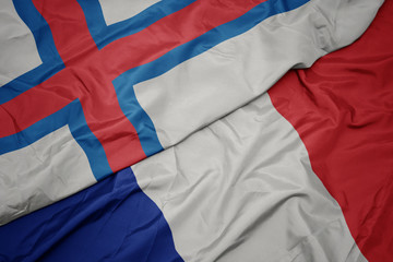 waving colorful flag of france and national flag of faroe islands.