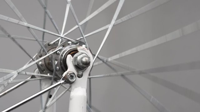 The rotation of the front wheel of the bike. Front hub with knitting needles close-up. A gloved hand rotates a bicycle wheel.