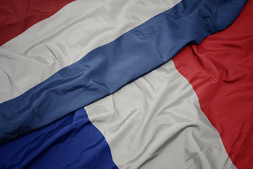 waving colorful flag of france and national flag of netherlands.