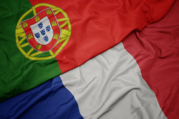 waving colorful flag of france and national flag of portugal.
