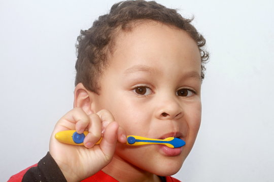 boy brushing his teeth with an electric tooth brush with grey background stock image stock photo