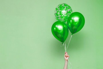 stylish birthday party or holidays with balloons. three green balloons on the green background with...