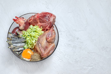 Natural raw dog food BARF diet in bowl Meat bone organs fish poultry egg vegetables organic food supplement