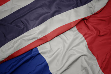 waving colorful flag of france and national flag of thailand.