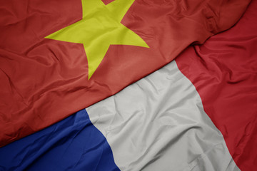 waving colorful flag of france and national flag of vietnam.