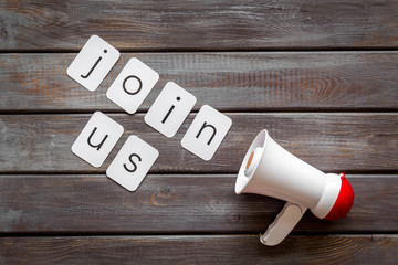 Join us announcement symbol with megaphone and text on wooden background top view