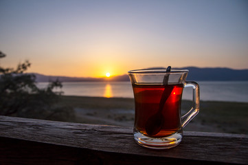 Glass cup of Turkish tea during sunset of Burdur lake in Turkey