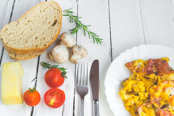 Omelet with bacon and mushrooms on white table. High angle view