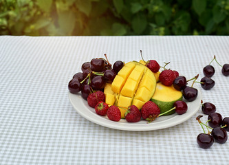 Fruit salad with fresh sweet cherry, mango and croissants on the table  white background. Flat lay, concept composition brackfast