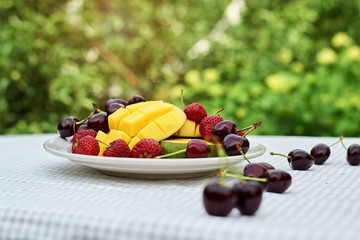 Fruit salad with fresh sweet cherry, mango and croissants on the table  white background. Flat lay, concept composition brackfast