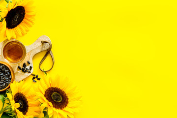 Fresh sunflower oil with seeds and flower frame on yellow background top view mock up