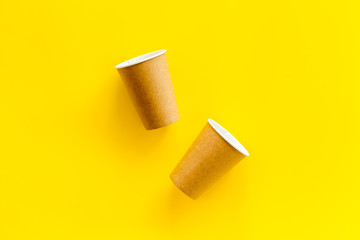 Empty paper cups for coffee to-go from cafe on yellow background top view mockup