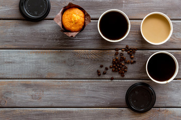 paper cups with black coffee and cappuccino to take away, beans, muffin on wooden background mock-up