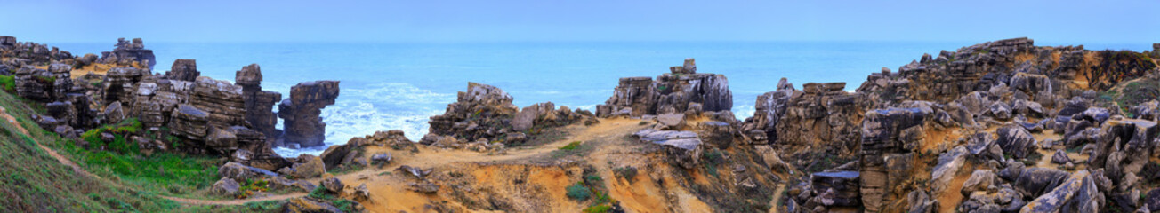 A huge ocean waves breaking on the coastal cliffs in at the cloudy stormy day. Breathtaking romantic panoramic seascape of ocean coastline. Peniche, Portugal.