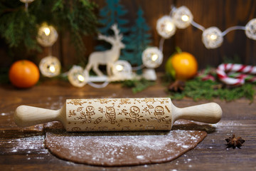 Rolled dough with rolling pin on wooden table covered with baking flour.