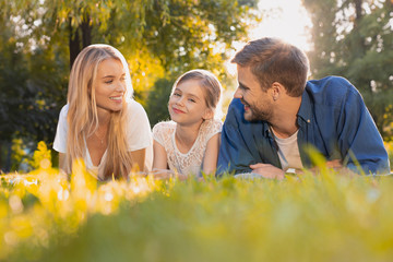 Beautiful happy family enjoying moment while lying on green grass in park