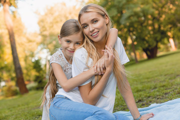 Happy young mother with her daughter hugging at park