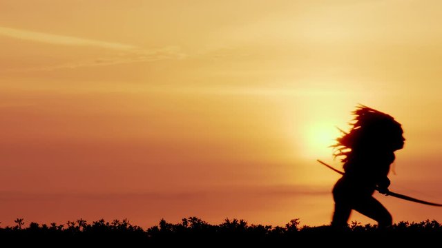 silhouette of Native American archery while hunting at sunset. Native American shoots from a bow while hunting.