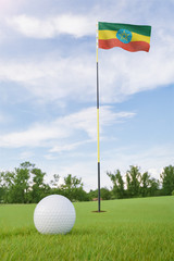 Obraz premium Ethiopia flag on golf course putting green with a ball near the hole