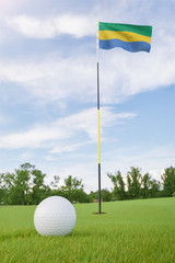 Obraz premium Gabon flag on golf course putting green with a ball near the hole