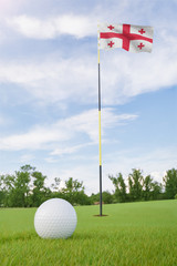 Obraz premium Georgia flag on golf course putting green with a ball near the hole