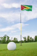 Obraz premium Guyana flag on golf course putting green with a ball near the hole