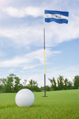 Obraz premium Honduras flag on golf course putting green with a ball near the hole