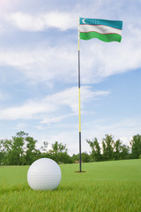 Obraz premium Uzbekistan flag on golf course putting green with a ball near the hole
