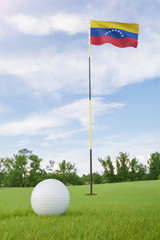 Obraz premium Venezuela flag on golf course putting green with a ball near the hole