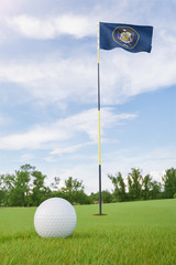 Obraz premium Utah flag on golf course putting green with a ball near the hole