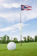 Obraz premium Ohio flag on golf course putting green with a ball near the hole