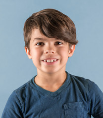Smiling young boy with big grown up teeth isolated on blue background © ShannonK