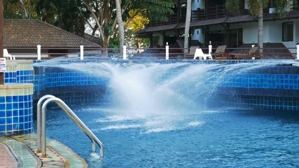 fountain in the pool splashes water in the summer in the heat