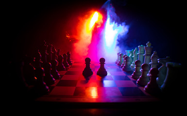 Chess board game concept of business ideas and competition. Chess figures on a dark background with smoke and fog.