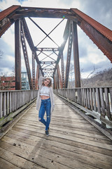 Stunning young female model poses on bridge with sun shining above